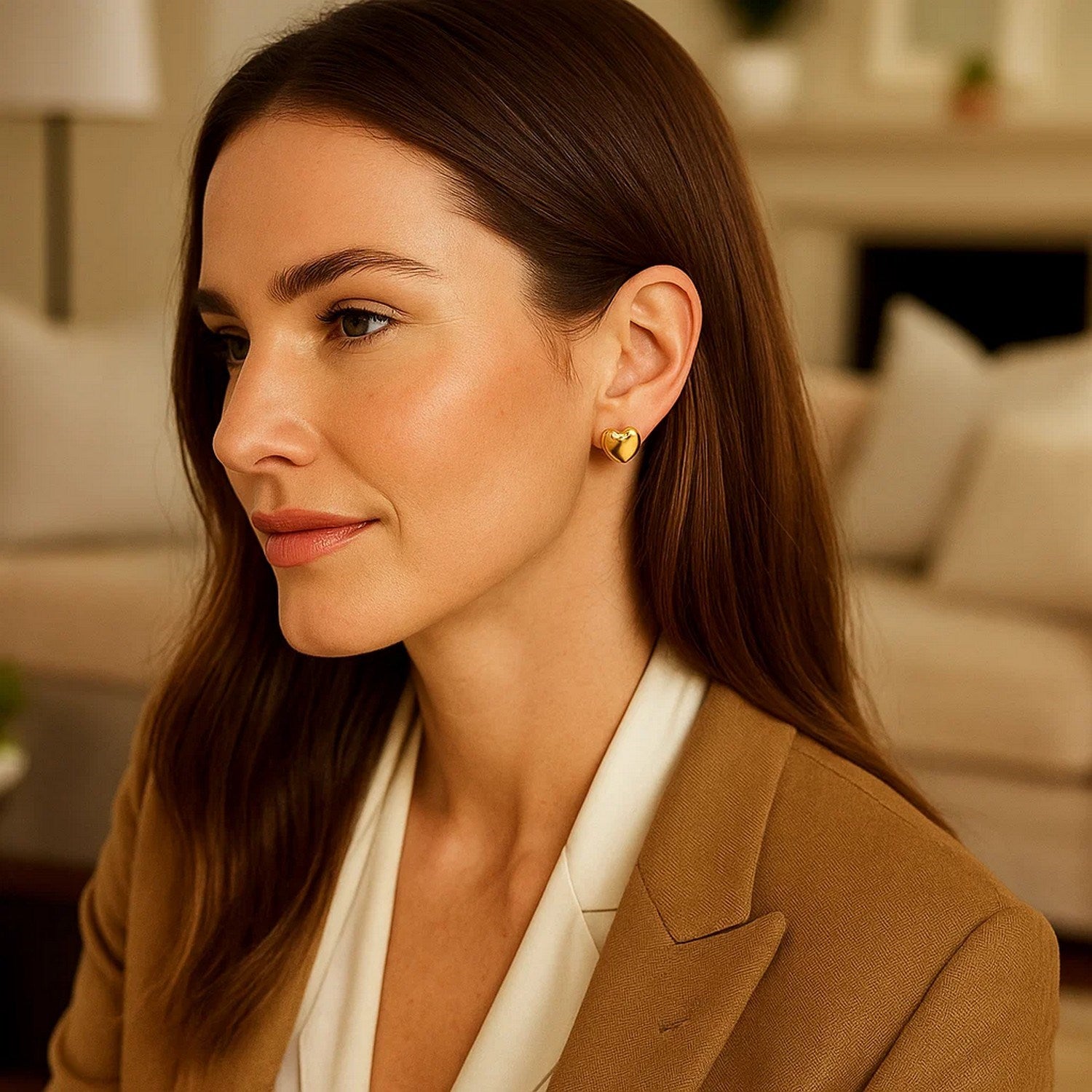 Puffed heart stud earrings in 14K yellow gold on a woman's ear.