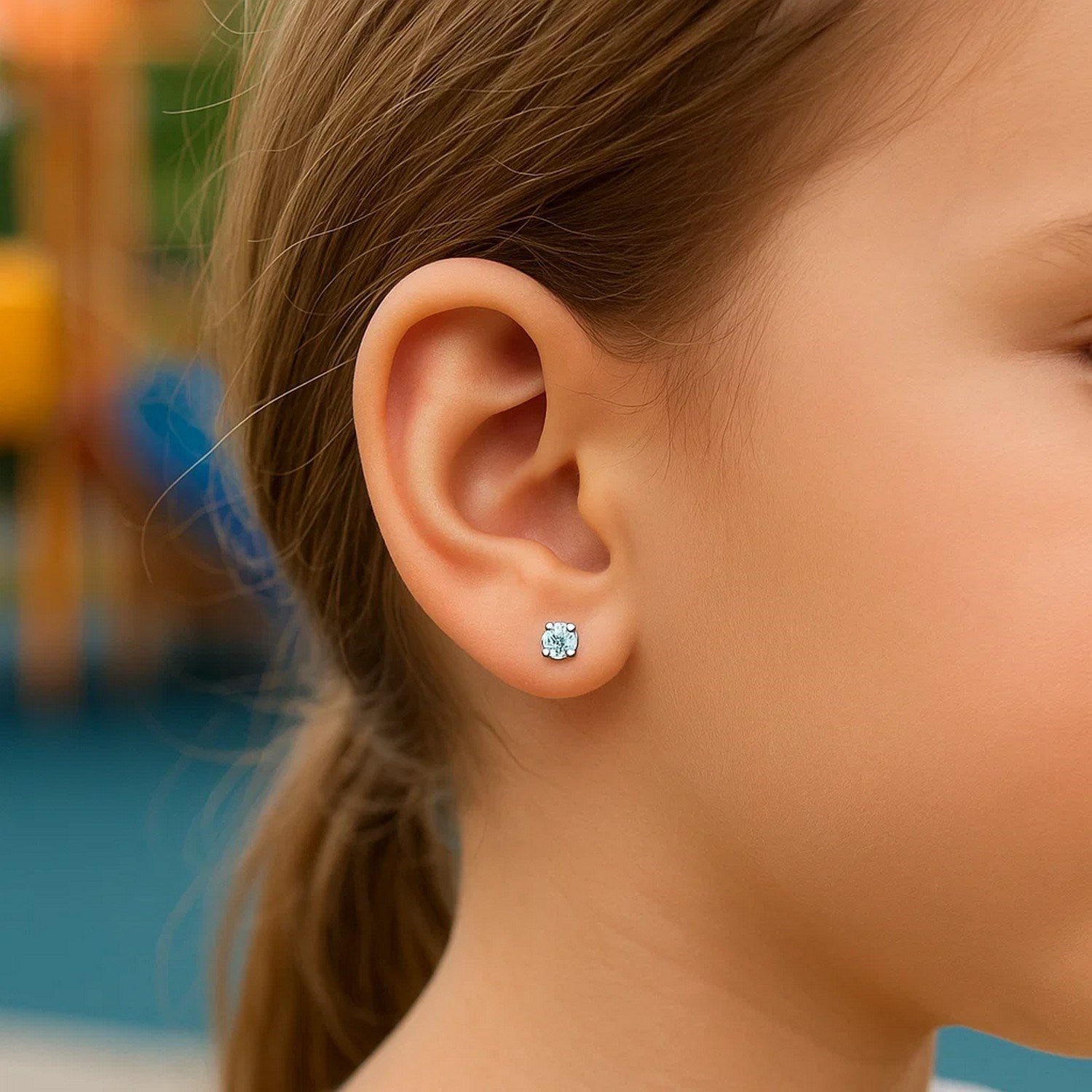 A child wears a 14k white gold stud earring with a white cubic zirconia.