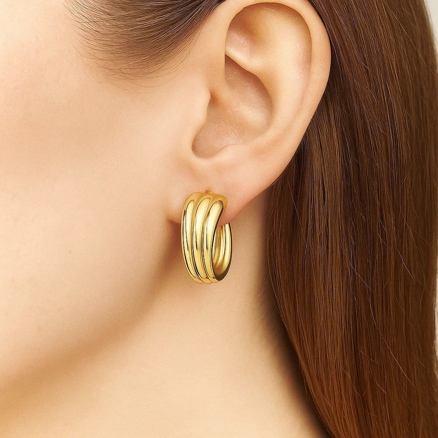 14K yellow gold 3-row graduated hoop earring on a model's ear.