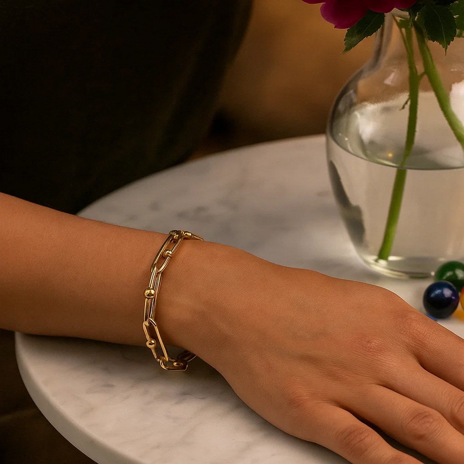 14k yellow gold beaded oval chain bracelet on a person's wrist.