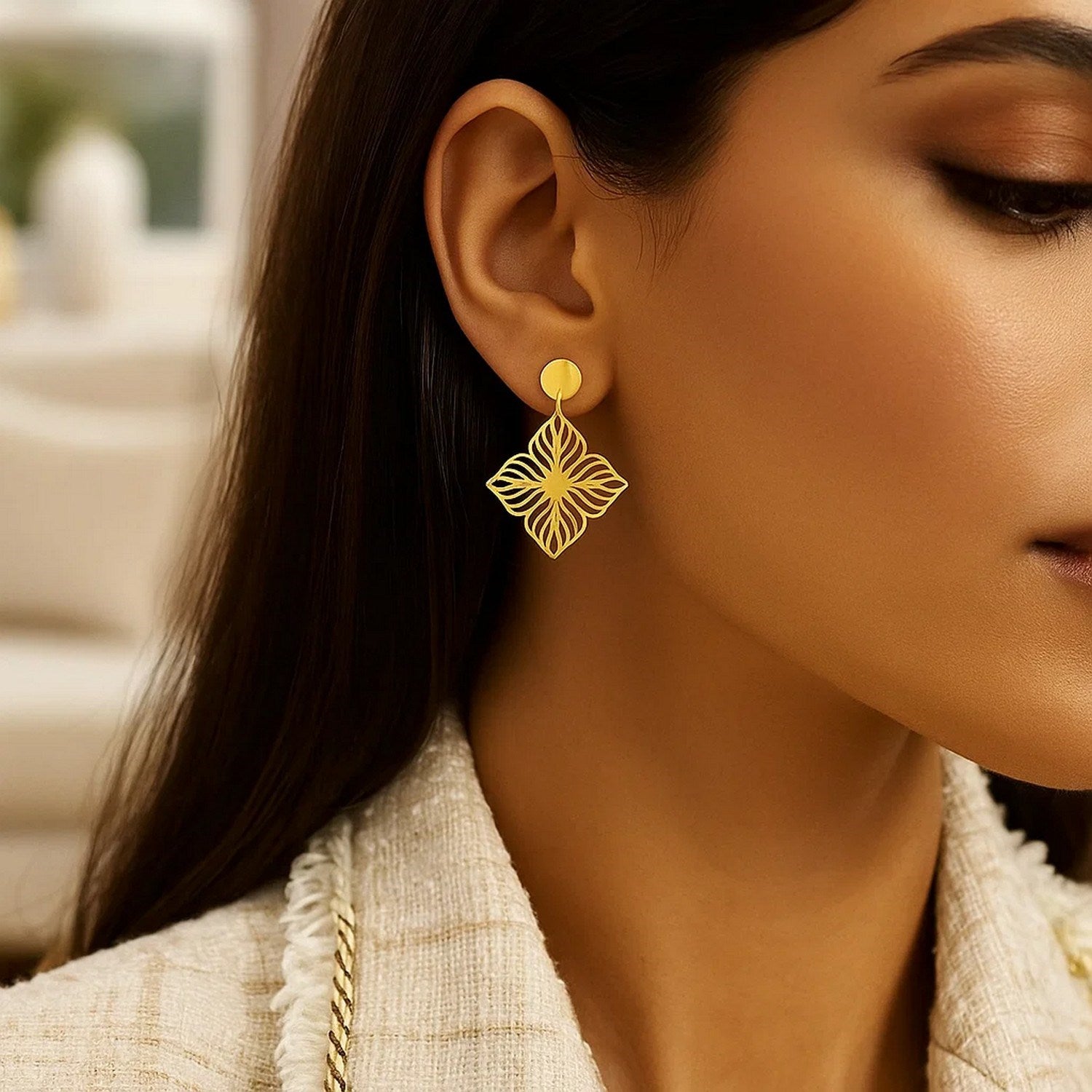 14K yellow gold high polish flower cutout earrings on a woman's ear.