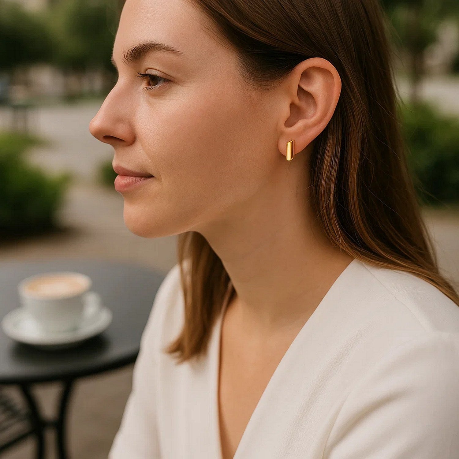 14k yellow gold polished rectangular post earrings on a woman's ear.
