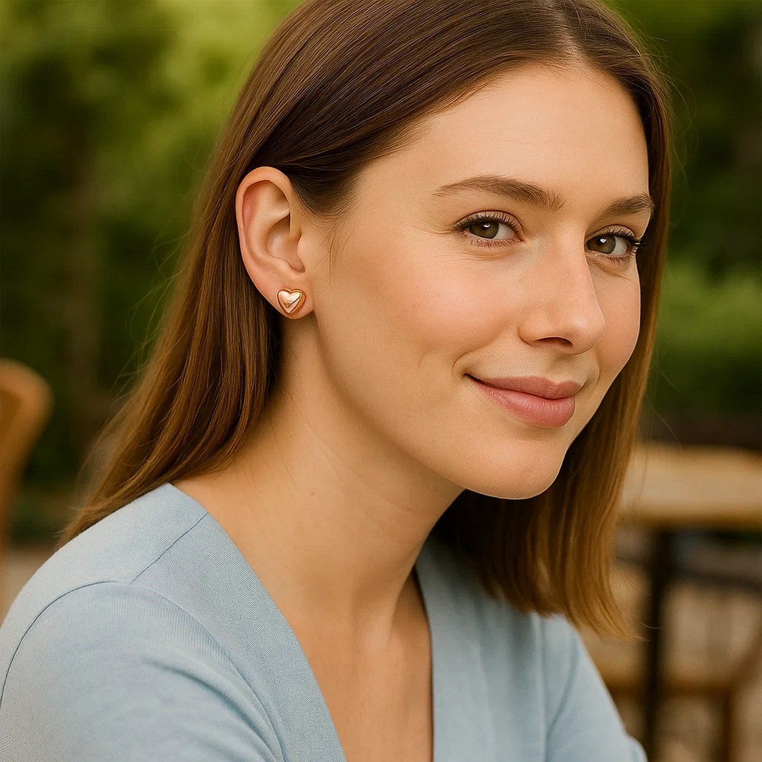14k rose gold puffed heart shape shiny earrings on a woman.