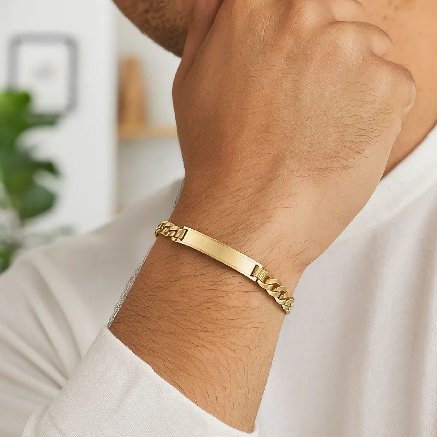 A man wears a 14k yellow gold curb ID bracelet on his left wrist.