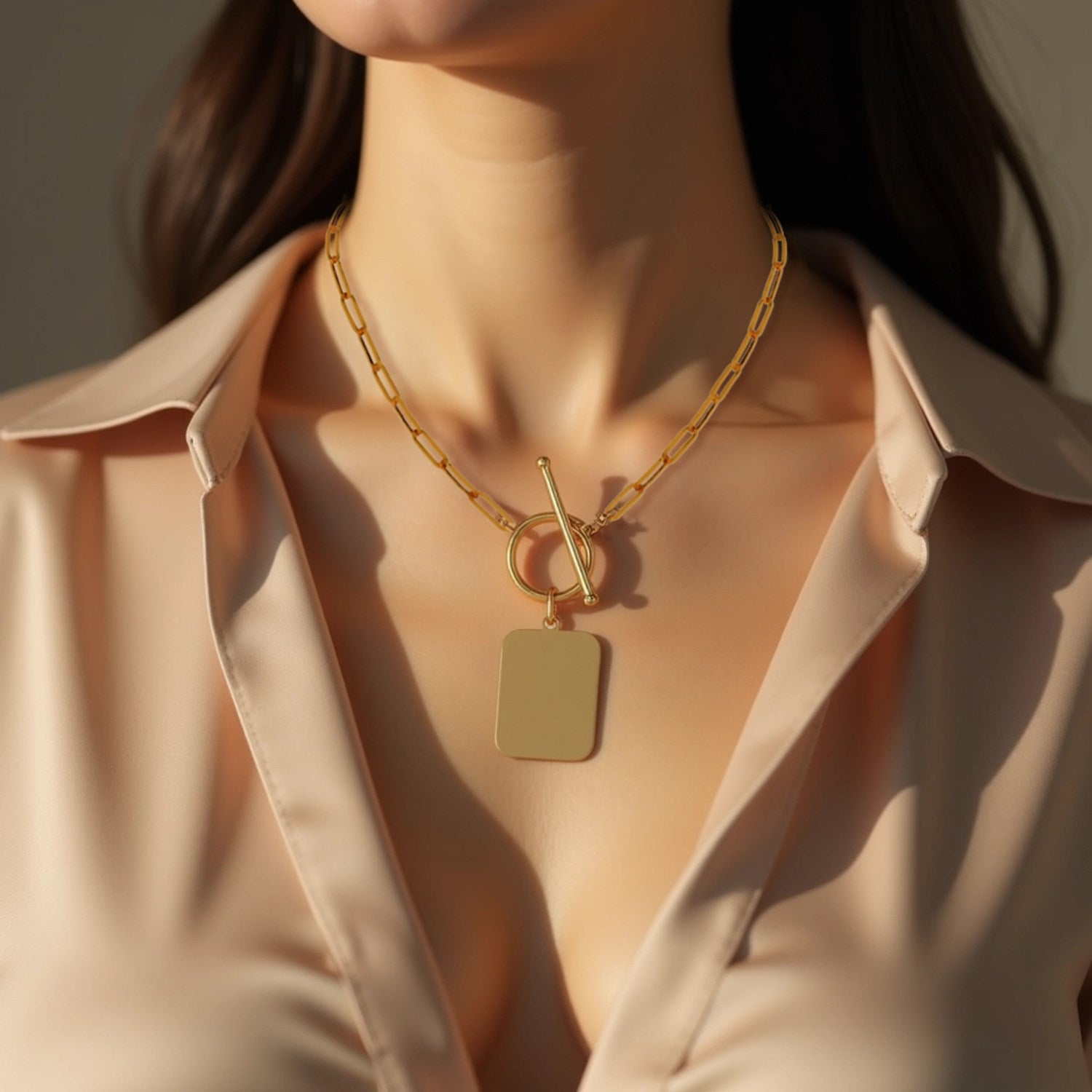 14k yellow gold paperclip chain necklace with a rounded rectangle pendant and toggle clasp.