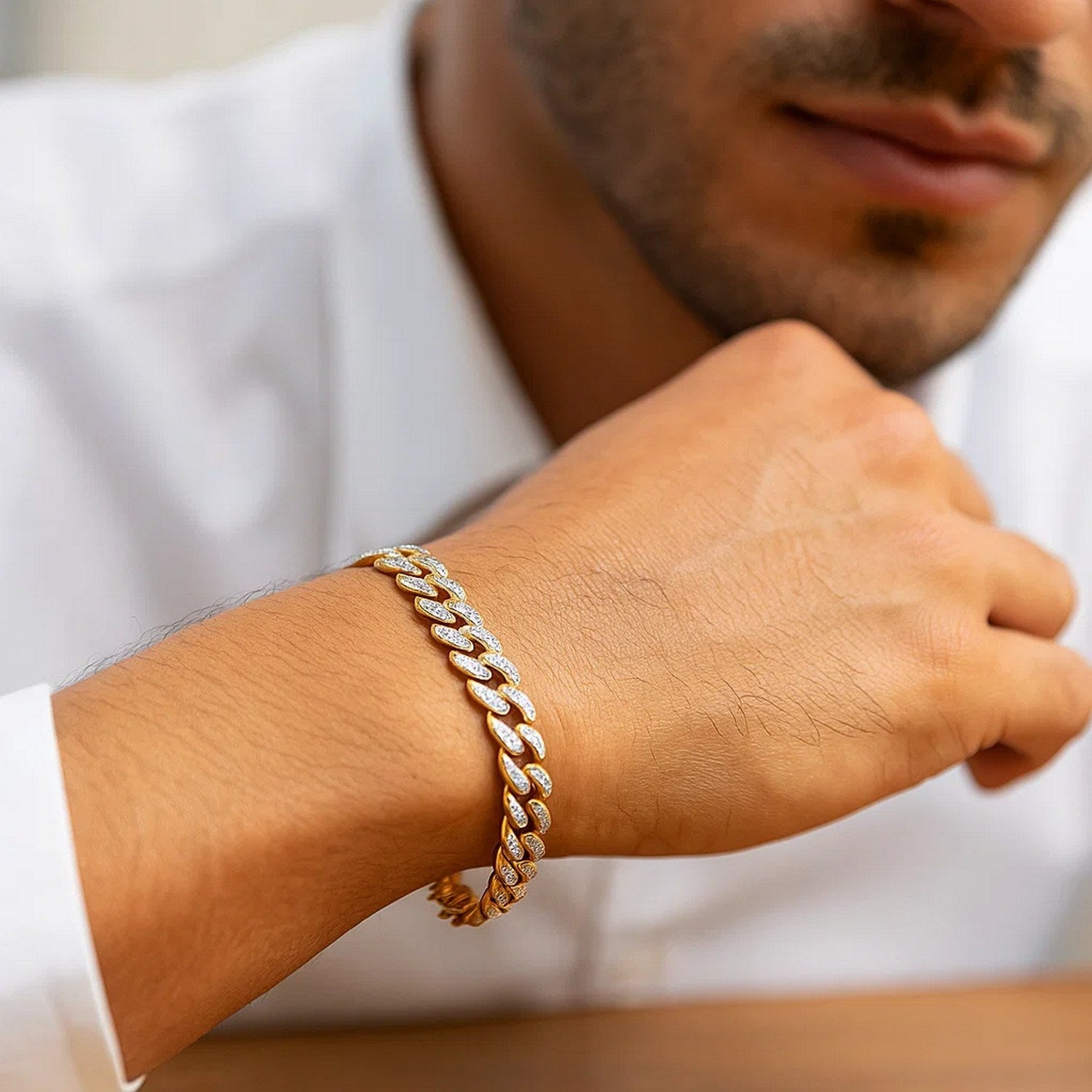 A 14k two-tone gold curb chain bracelet with diamond pave links on a man's wrist.