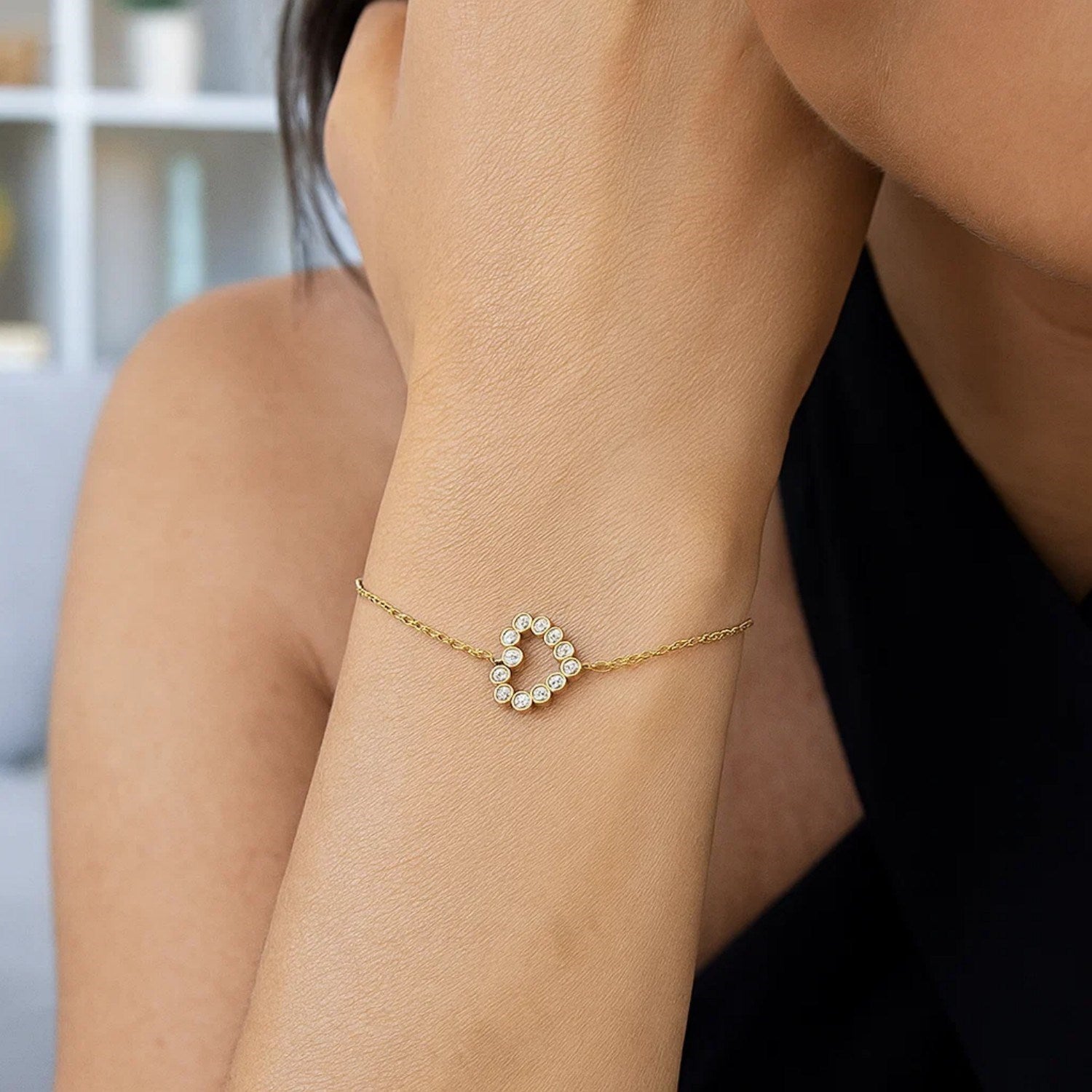 Elegant 14k yellow gold petite diamond heart bracelet on a person's wrist.