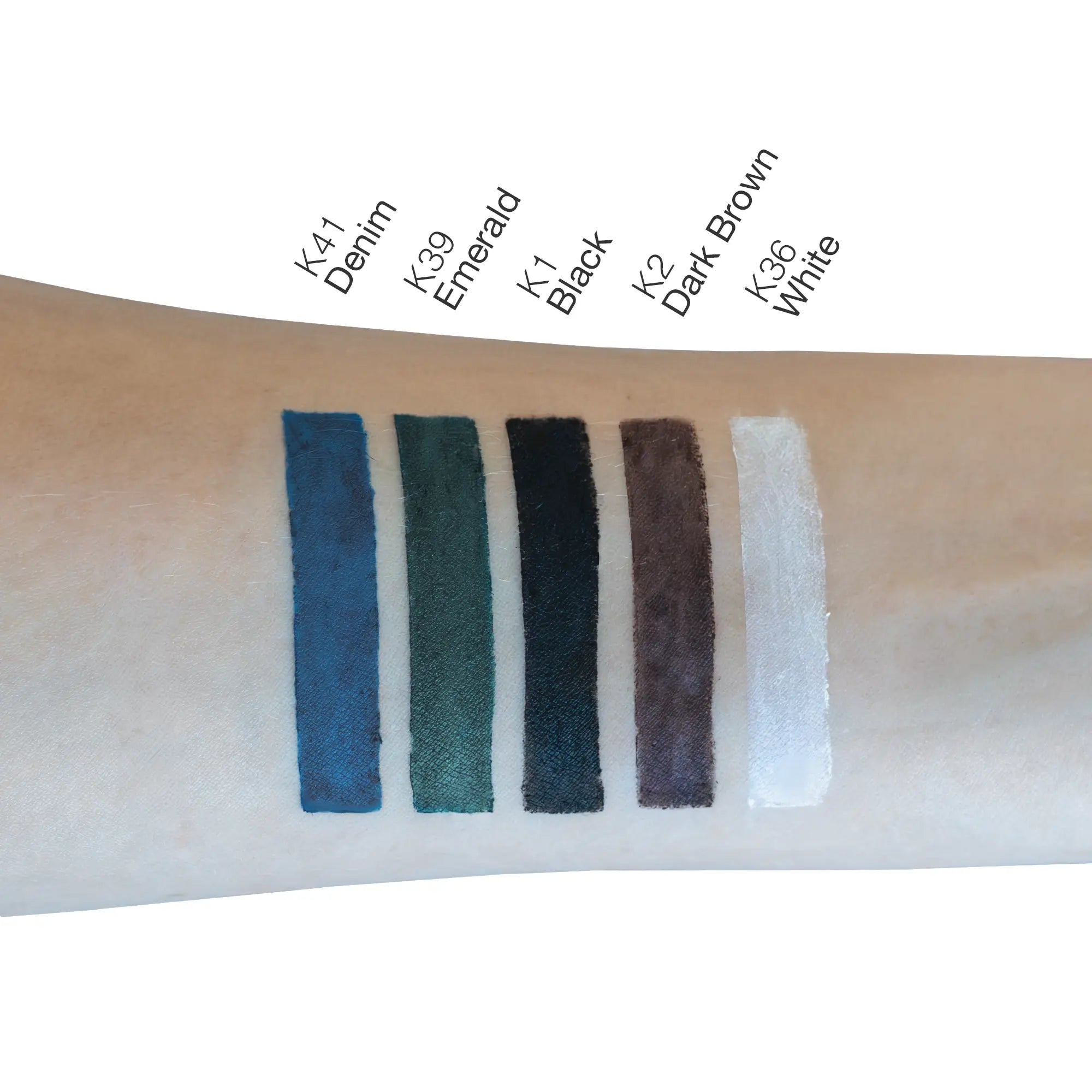 Six swatches of eyeliner in denim, emerald, black, dark brown, and white on an arm.